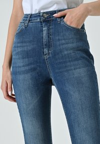 Jeans in denim blu a vita alta con un design classico; presentano tasche anteriori, chiusura con bottone e una leggera scoloritura per aggiungere texture.