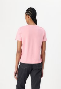 Rosa bomulds t-shirt med rund halsudskæring og korte ærmer, der har en afslappet pasform. Bagsiden har en glat overflade og et simpelt design.