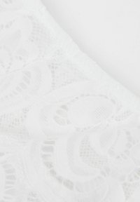Tissu en dentelle blanche avec des motifs floraux complexes. Présente une texture délicate et une apparence douce et transparente, adaptée aux designs de vêtements élégants.