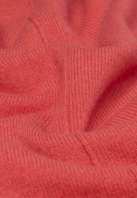 Korallenfarbener Strickstoff mit einer weichen, strukturierten Oberfläche. Verfügt über ein geripptes Muster und sanfte Falten, die Tiefe und Weichheit präsentieren.