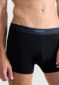 Boxer briefs Sloggi neri con una morbida cintura elastica, caratterizzati da una texture del tessuto liscia e un design aderente.