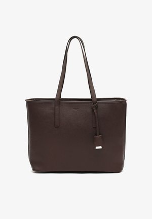 Bruine leren draagtas met twee lange handvaten, rechthoekige vorm, gestructureerd oppervlak en een klein hangertje. Geen zichtbare metalen accenten.