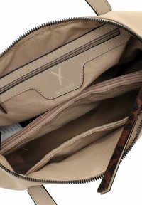 Interno di una borsa beige con diversi scomparti con zip e aperti, etichetta in pelle con marchio e una linguetta della zip con stampa leopardata.