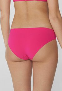 Braguitas de bikini rosas con una textura suave, corte a media altura y detalles de costura mínimos, diseñadas para confort y cobertura.