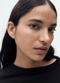 Close-up of a person with medium skin tone and straight black hair, wearing a black sweater, featuring smooth skin, brown eyes, and neutral lips.