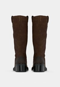 Bottes en cuir marron jusqu'au genou avec une texture douce, des anses à l'arrière et un talon noir épais. Construction robuste et design classique.