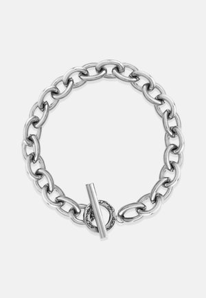 Hõbedane metallketi käevõru suurte omavahel kinnituvaid linkidega ja nööpkinnitusega, millel on ringikujuline aksessuaar. Siledat tekstuuri ja läikiv viimistlus.