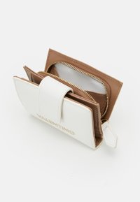 Portefeuille bifold compact en cuir texturé blanc avec un intérieur marron. Comprend une fermeture éclair dorée, un fermoir à pression et plusieurs compartiments.