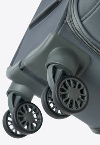 Rolkoffertje met gestructureerde grijze stof, drie zwarte wielen met ingewikkeld spaakontwerp en een versterkte basis voor stabiliteit.