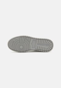 Gray rubber sneaker sole featuring a textured, circular pattern with ridges and a flat heel base, designed for traction and durability.
