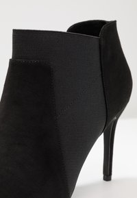 Schwarze Knöchelstiefel mit Wildlederoberfläche, elastischem Einsatz und hohem Stiletto-Absatz. Verfügt über nahtlose Nähte und eine elegante Silhouette.