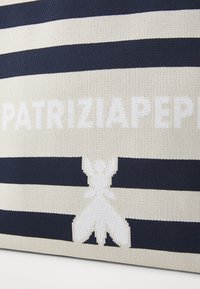 Prugasta torba v mornarski modri in kremni barvi, z teksturirano tkanino, poudarjenim logotipom "PATRIZIA" in belim emblemom na dnu.