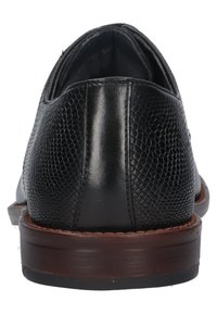 Chaussures en cuir noir avec une finition texturée à motif reptile, un bout arrondi et une semelle en bois brun. Une couture soignée autour des bords.