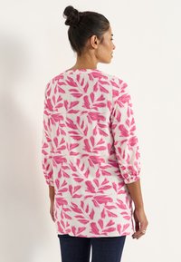 Langsleeve shirt van lichtgewicht stof, met roze bladerenpatronen op een witte achtergrond, elastiche mouwen en een rechte snit.