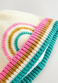 Strikket hat med en cremefarvet bund, der har pink, guld og turkise fletmønstre samt et struktureret bånd med vandrette striber.