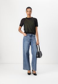Black sheer knit top, high-waisted wide-leg blue jeans, and black heels. Holding a small black handbag. Simple, textured, and clean lines.