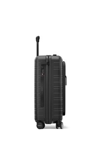 Valise rigide noire avec des stries horizontales, poignée rétractable, serrure à combinaison et quatre roues pivotantes pour la mobilité.