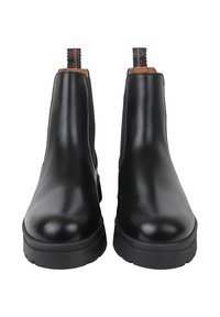 Stivaletti alla caviglia in pelle nera con pannelli laterali elastici, punta rotonda e suola in gomma spessa. Dotati di una linguetta con cuciture decorative.