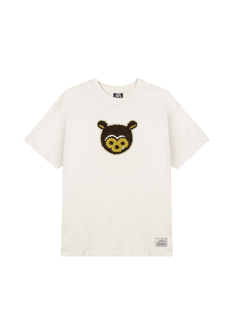 Camiseta de algodón en color crema con un diseño de cara de oso marrón en la parte delantera. Mangas cortas, cuello redondo y una pequeña etiqueta de la marca en la parte inferior izquierda.