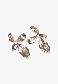 Cercei din metal de nuanță argintie, modelați în formă de petale florale, cu o suprafață texturată și modele lungi, fluide.