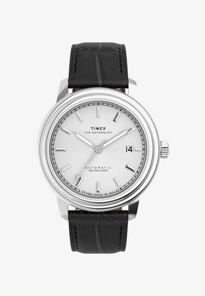 Timex Waterbury watch with a silver stainless steel case, white dial, black crocodile-pattern leather strap, and date display at 3 o'clock.
