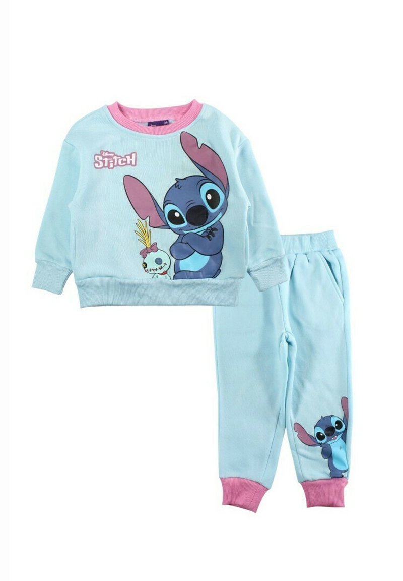 Survêtement en coton bleu clair avec manches longues et pantalon, comportant un motif de personnage cousu. Accents roses sur les poignets et le col.