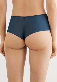 Marineblauwe high-waisted slips gemaakt van gladde stretchstof met een naadloos ontwerp, voorzien van minimalistische stiksels en een comfortabele pasvorm.