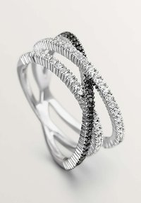 Anillo de plata con tres bandas entrelazadas; una con piedras negras, las otras con piedras transparentes, todas con un acabado texturizado y bordes pulidos.