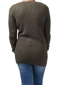 Pull vert olive avec une texture tricotée, manches longues et ourlet côtelé, présentant une coupe ample et un dos ouvert.