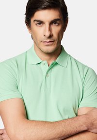 Jasnozielona koszulka polo z klasycznym kołnierzykiem, dwoma guzikami i krótkimi rękawami. Teksturowana tkanina z dopasowanym fasonem.