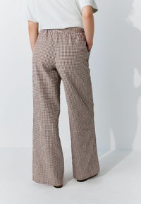 Bruine en witte geruite wijde broek met een elastische tailleband en zijzakken, met een gladde textuur.