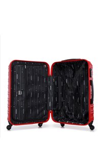 Maleta rígida roja con cuatro ruedas, abierta para revelar un interior forrado en negro que cuenta con una correa elástica en forma de cruz y un bolsillo con cremallera.