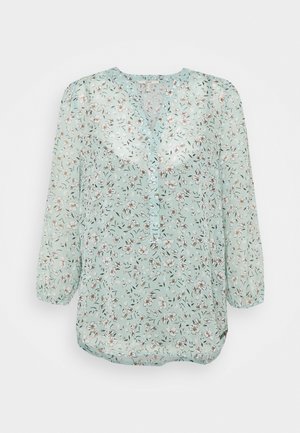 Hellgrüne Blumenbluse mit langen Ärmeln, rundem Ausschnitt und kleinen Knopfdetails vorne.