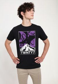 Maglietta nera con una grafica che presenta una montagna bianca e dettagli viola. Mostra il testo "TWNTY7" in bianco sotto la grafica.