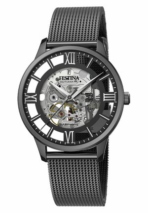 Black automatic watch with a transparent case revealing inner mechanisms. Features a mesh band, large Roman numeral markers, and sapphire glass.