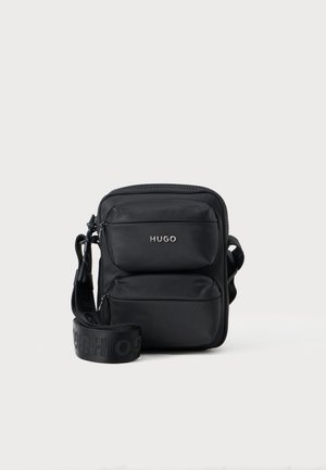 Borsa a tracolla in nylon nera con due tasche frontali con zip, tracolla regolabile con logo e finitura opaca liscia. Forma rettangolare compatta.