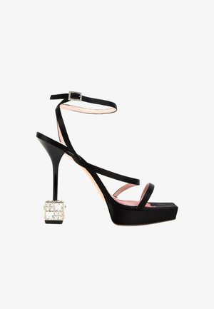 Sandale noire à talon haut avec fines brides, boucle à la cheville, semelle plateforme et talon carré orné de gros cristaux transparents.