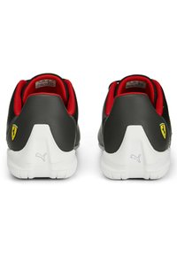 Černé kožené tenisky s červenými akcenty, zaoblený tvar, bílá gumová podešev a výrazné logo Ferrari na patě. Texturovaný povrch.