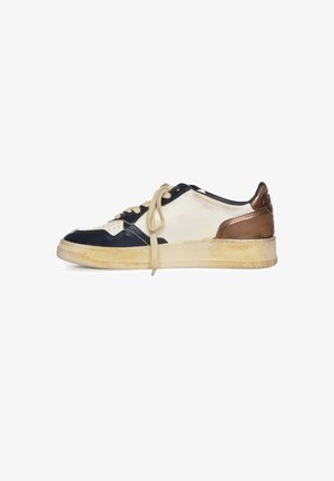 Sneaker met beige, zwarte en bronzen panelen, beige veters en een licht versleten rubberen zool, zijaanzicht op een witte achtergrond.