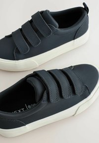 Baskets bleu marine avec trois bandes Velcro, en matériau synthétique lisse, semelles en caoutchouc blanc et motifs de grip texturés.
