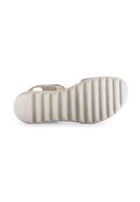 Schoenen met een rubberen zool voorzien van horizontale groeven, beige banden en een gevoerd ontwerp voor comfort. Merkenlogo zichtbaar op de zool.