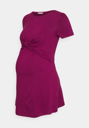 Magenta zwangerschapsjurk met korte mouwen, een knoopdetail aan de voorkant en een aansluitende buste, ontworpen voor een zwangere silhouet.