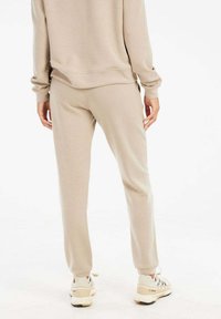 Beige Jogginghosen mit schmalem Schnitt und elastischem Bund, aus weichem Baumwollmischgewebe gefertigt. Sie zeichnen sich durch eine glatte Textur und ein minimalistisches Design aus.