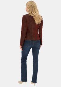 Czerwona kurtka o fakturowej powierzchni z dopasowanym krojem, zestawiona z ciemnoniebieskimi dżinsami. Posiada klapowany kołnierz i długie rękawy, prezentując gładki materiał.