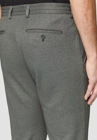 Pantalon gris en tissu texturé, avec une poche arrière à fermeture boutonnée, des passants de ceinture et une coupe ajustée.