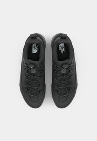 Black outdoor shoes with a textured upper, elastic laces, and padded collar. The insoles feature a logo in light gray. Rubber outer sole.