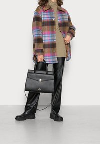 Chaqueta oversized de cuadros marrón, suéter de punto marrón claro, pantalones de cuero negros, botas negras gruesas y un bolso estructurado negro.