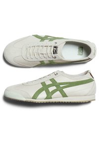 Tenisky s krémovým koženým svrškem, zelenými semišovými akcenty a textured gumovou podrážkou. Obsahují kulaté šňůrky a klasický design.