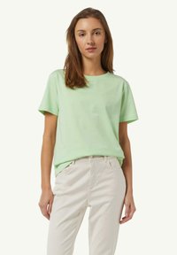 Light green short-sleeve t-shirt in soft cotton fabric with a round neck. Minimal design, paired with light beige pants.