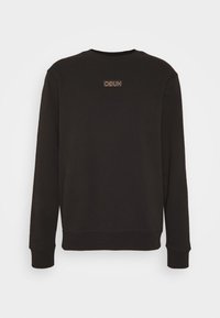 Sudadera negra con mangas largas y cuello redondo. Logo bordado en un parche rectangular en el centro. Textura suave.